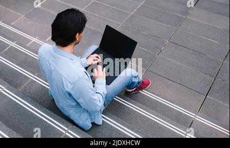 Man using laptop sitting on steps Stock Photo