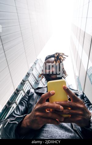 Smiling man text messaging on smart phone in city Stock Photo