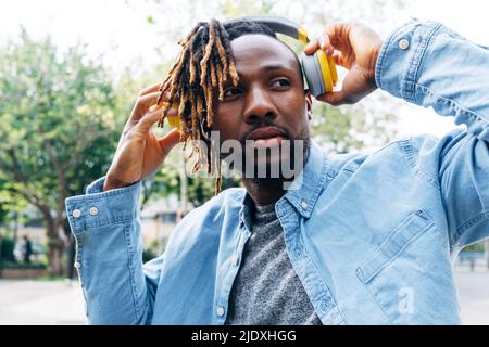 Thoughtful man wearing wireless headphones Stock Photo