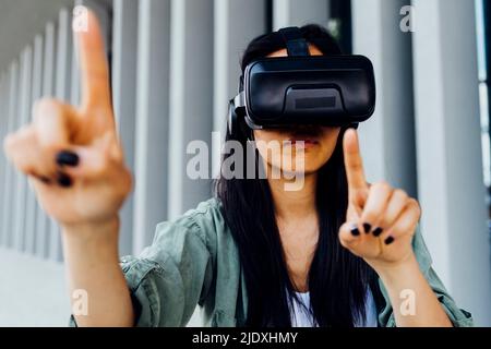 Young woman wearing VR simulator pointing Stock Photo