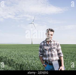 Engineer with tablet PC standing in front of wind turbine Stock Photo