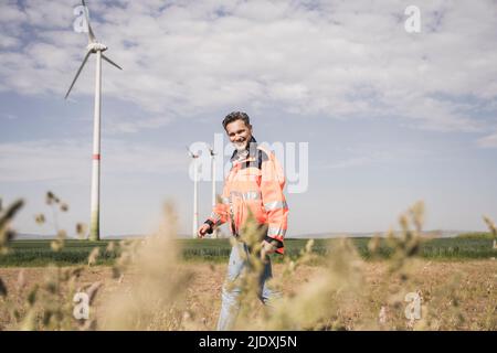 Smiling engineer walking at field on sunny day Stock Photo