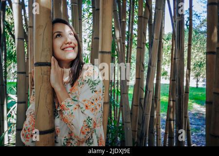 Smiling young woman looking up standing in bamboo grove Stock Photo