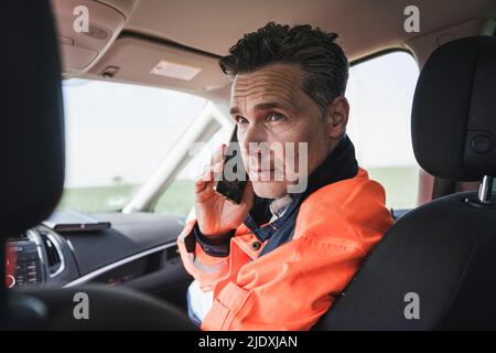 Engineer talking on mobile phone sitting in car Stock Photo