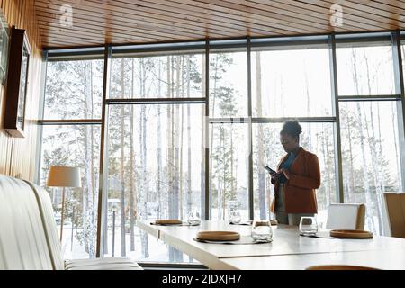 Businesswoman using smart phone standing by glass window Stock Photo