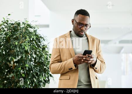 Young businessman text messaging through smart phone in office Stock Photo