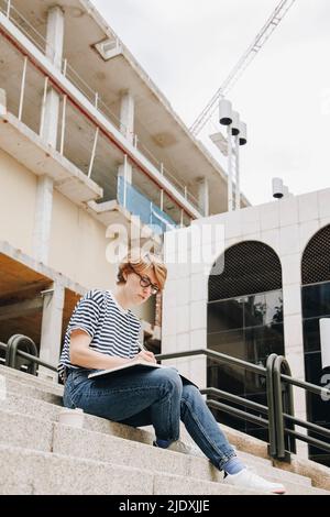 Businesswoman preparing strategy sitting on steps near building Stock Photo