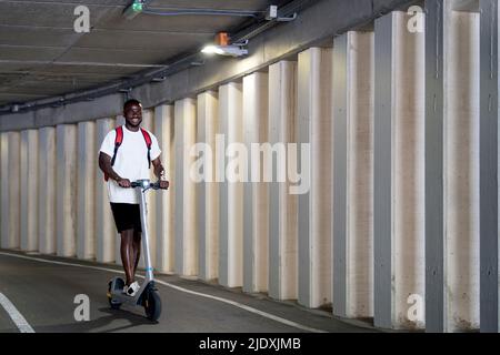 Young man riding electric scooter in tunnel Stock Photo