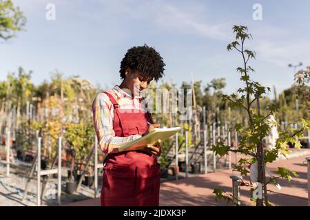 Smiling gardener preparing checklist at plant nursery Stock Photo