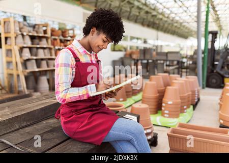 Young gardener preparing inventory sitting in warehouse Stock Photo