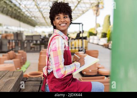 Happy gardener looking away preparing inventory in warehouse Stock Photo