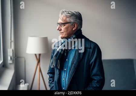 Thoughtful senior businessman looking through window at office Stock Photo