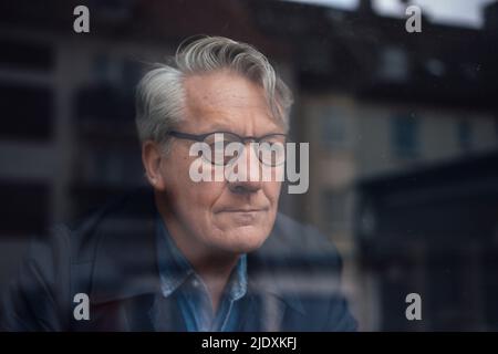Thoughtful senior businessman looking out of window Stock Photo