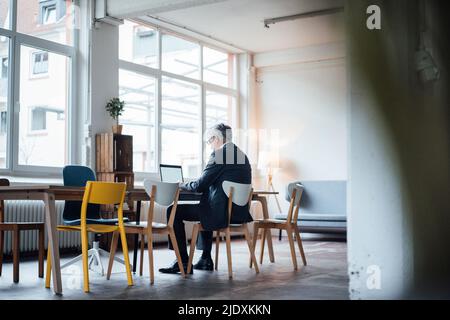Senior businessman using laptop at desk in office Stock Photo