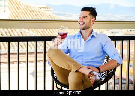 Happy man with wineglass sitting on balcony Stock Photo