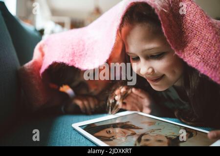 Boy lying with sister looking at photograph on tablet PC at home Stock Photo