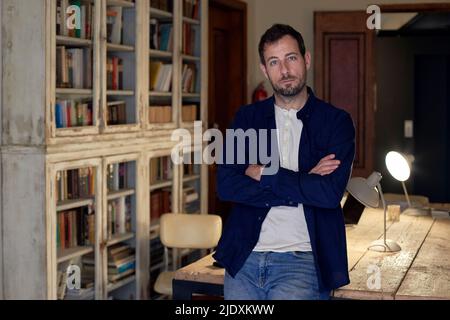 Businessman with arms crossed leaning on desk at home office Stock Photo