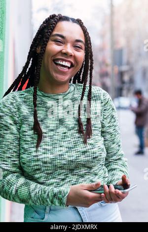Cheerful young woman standing with mobile phone Stock Photo