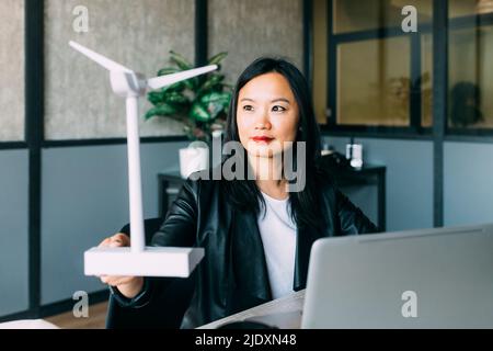 Mature businesswoman examining wind turbine model at office Stock Photo