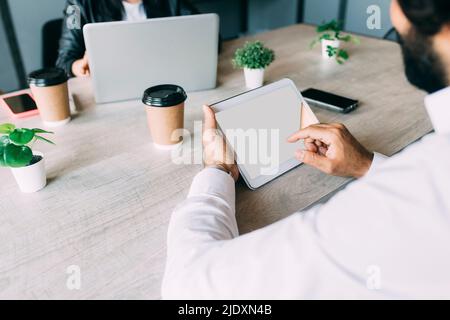 Businessman using tablet computer by colleague at work place Stock Photo