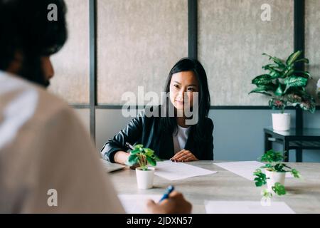 Smiling businesswoman talking with colleague in office Stock Photo