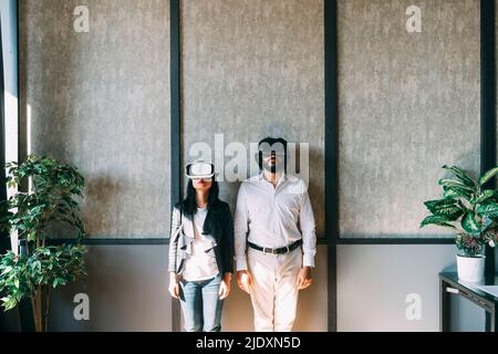 Business colleagues with VR glasses in front of wall at office Stock Photo