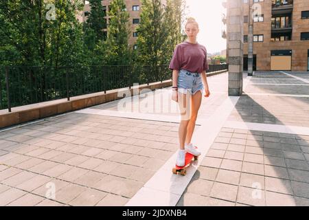 Teenage girl skateboarding on sunny day Stock Photo