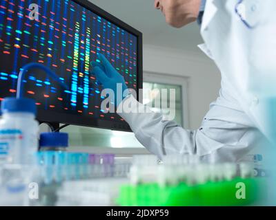 Scientist analyzing DNA on computer screen at laboratory Stock Photo