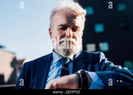 Senior businessman checking notification on smart watch Stock Photo