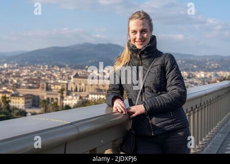 Smiling young woman standing by wall on sunny day Stock Photo