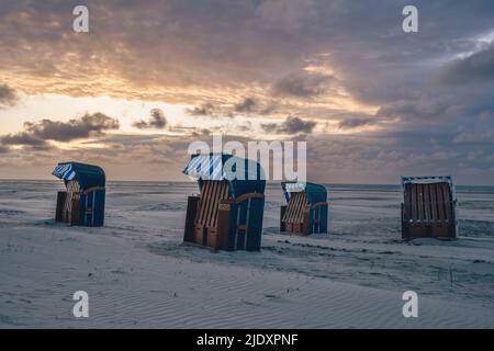 Germany, Lower Saxony, Juist, Hooded beach chairs on empty beach at sunset Stock Photo