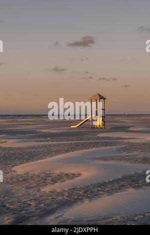 Germany, Lower Saxony, Juist, Slide on empty beach at dusk with clear line of horizon over North Sea in background Stock Photo