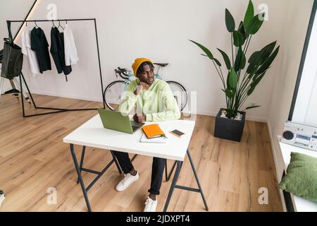 Young freelancer with hand on chin at home Stock Photo
