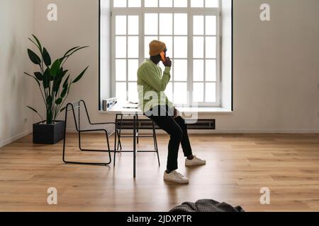 Young freelancer talking on smart phone at home Stock Photo
