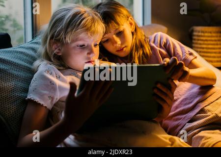 Sisters watching tablet PC at home Stock Photo