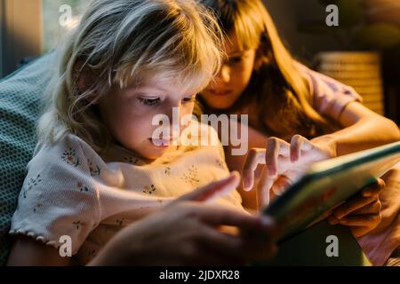Sisters using tablet PC together at home Stock Photo