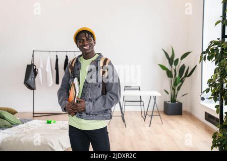 Smiling student with books in bedroom Stock Photo