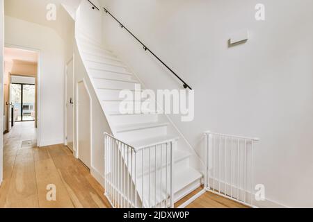 White staircase with a black handrail leading upstairs in the lobby of a modern apartment building Stock Photo