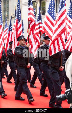 Manhattan, USA - 11. November 2021: FDNY marching with USA flags on Veterans Day Parade. NYC Firemen marching on red carpet. American Legion Stock Photo