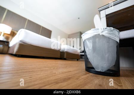 A container trash in the room with plastic inside it in hotel and resort bedroom with wooden floor and furniture background. Stock Photo