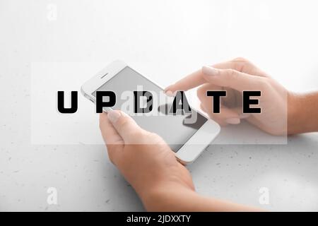 Hands with modern mobile phone on light background, closeup. Update concept Stock Photo