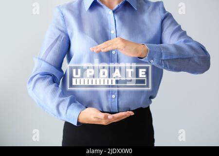 Businessman using virtual screen with word UPDATE and status bar on light background Stock Photo