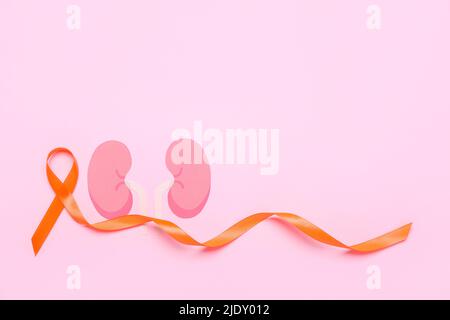 Orange awareness ribbon and paper kidneys on pink background Stock Photo