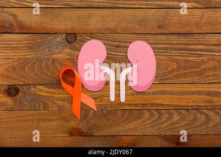 Orange awareness ribbon and paper kidneys on wooden background Stock Photo