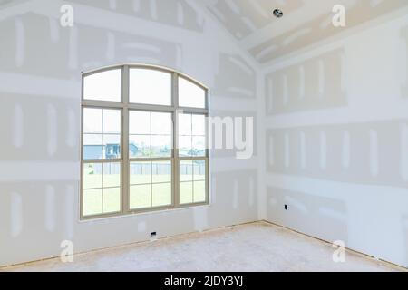 In an empty apartment room renovating a new house under construction, we are finishing the walls with putty Stock Photo