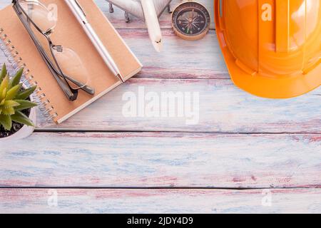 Flat lay photo with safety helmet,notebook,glasses,airplane toy,compass, pen and cuctus flower on wooden table background. Top view with copy space fo Stock Photo