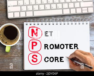 Top view text with NPS on notebook with pencil,keybroad and coffee on wood table background in office workplace. Business and financial concept. Stock Photo