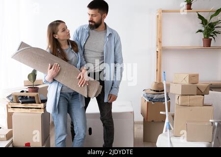 Young couple moving in new house, carrying a carpet, family in new apartment Stock Photo