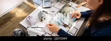 Person Watching Footage On Digital Tablet With Security Equipment On Blueprint Stock Photo