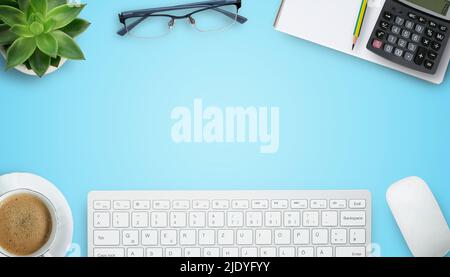 Office desk with stationary,keyboard,notebook,calculator,pencil,coffee and flower on blue table background. Top view with copyspace. Concept for busin Stock Photo